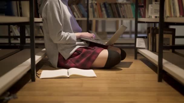 Inclinazione fino colpo di ragazza con la gonna rossa seduto sul pavimento in biblioteca — Video Stock