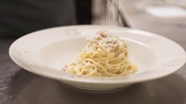 Servis etmeye hazır bir plaka içinde Carbonara spagettiye parmesan ekleme yakın çekim
