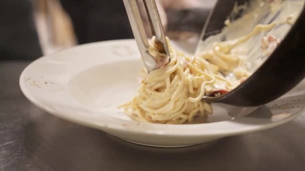 Nahaufnahme von Spaghetti Carbonara mit einer Zange in eine weiße Servierschüssel — Stockvideo