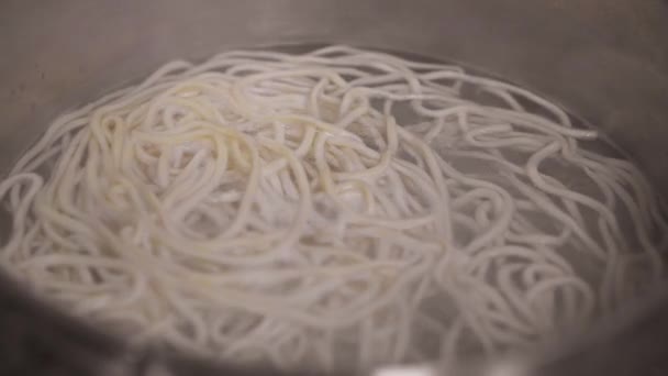 Cierre de espaguetis de pasta laminada en agua hirviendo — Vídeos de Stock
