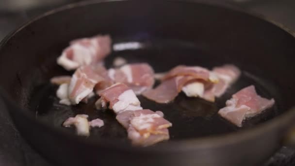 Primo piano di una fetta di pancetta cotta in una padella di ghisa nera — Video Stock