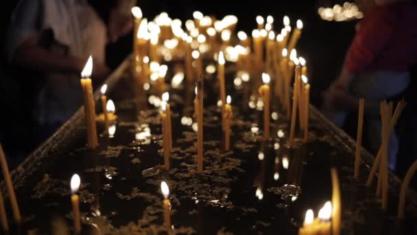 Hořící svíčky střední záběr v naprosté tmě lidí na pozadí — Stock video