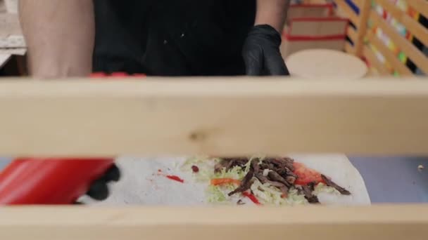 Cozinhe as mãos em luvas azuis envolvendo shawarm no mercado de comida de rua — Vídeo de Stock