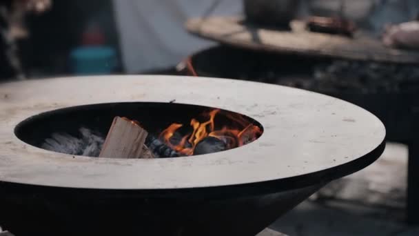 Zeitlupe des Kochs legt Brennholz in runden Gusseisen-Grill — Stockvideo