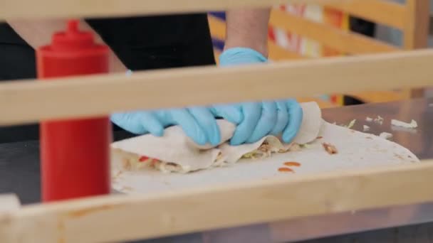 Cook handen in blauw handschoenen shawarm op straatvoedsel markt verpakken — Stockvideo