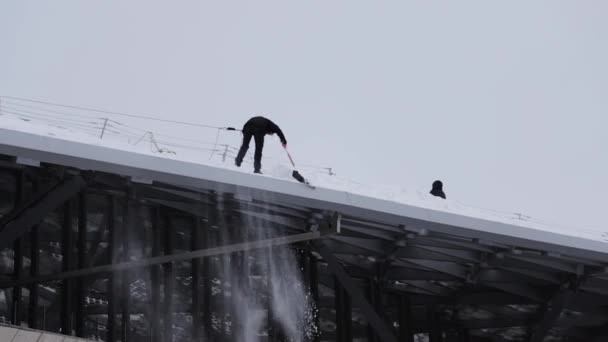 Pracownik w hemlet i zamontować śnieg rzucanie z dachu budynku — Wideo stockowe