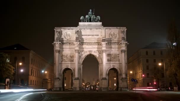 MUNICH, ALEMANIA - 10 DE NOVIEMBRE DE 2018: Timelapse of Victory Arch of the Bavarian Army at night, Munich, Germany. Tráfico nocturno ocupado en Munich cerca de Victory Arch . — Vídeo de stock