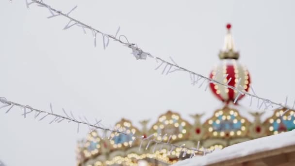 Handheld close up shot of white garlands hanging outside near carousel — Stock Video