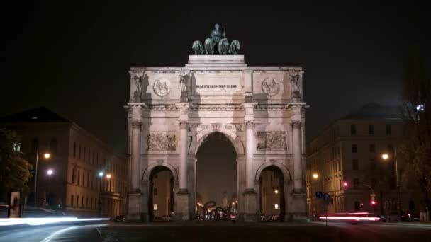 MUNICH, ALEMANIA - 10 DE NOVIEMBRE DE 2018: Timelapse of Victory Arch of the Bavarian Army at night, Munich, Germany. Tráfico nocturno ocupado en Munich cerca de Victory Arch. Disparo de zoom — Vídeos de Stock