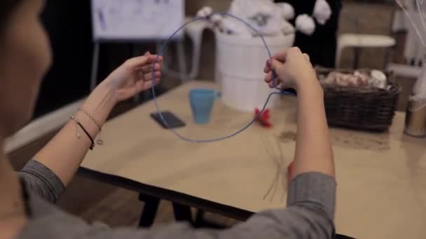 Manos femeninas tejiendo guirnalda sosteniendo un cable azul flexible — Vídeos de Stock