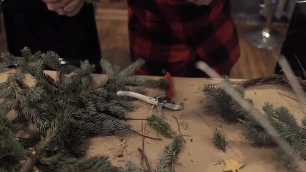 Руки женщины раскладывают сосновые ветви для рождественского венка — стоковое видео