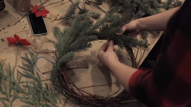 Жіночі руки затягують соснові гілки на різдвяному вінку — стокове відео