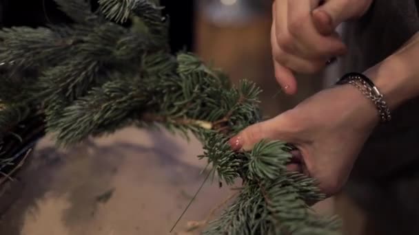 Vrouwelijke handen aanscherping van houten staven met een groene draad maken van de kroon van Kerstmis — Stockvideo