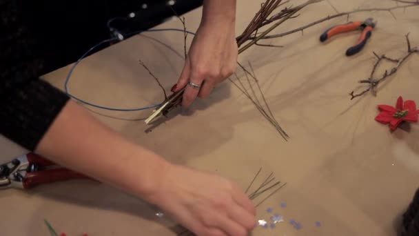 Vrouwelijke handen toetreden houten staven met een blauwe draad maken krans — Stockvideo