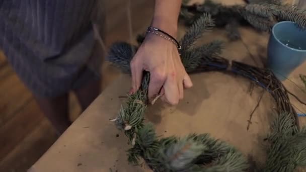 Γυναικεία χέρια που σφίγγουν τις ξύλινες ράβδους με ένα νήμα που φτιάχνει Χριστουγεννιάτικο στεφάνι — Αρχείο Βίντεο