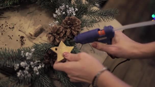 Закрытие женских рук, склеивающих звезды на рождественском венке — стоковое видео