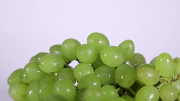 Bagas de uvas verdes em gotas de água que giram sobre a mesa — Vídeo de Stock