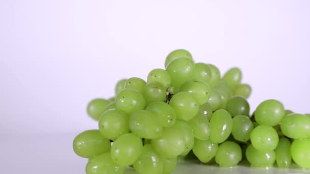 Bär av gröna druvor i vattendroppar som roterar på bordet — Stockvideo