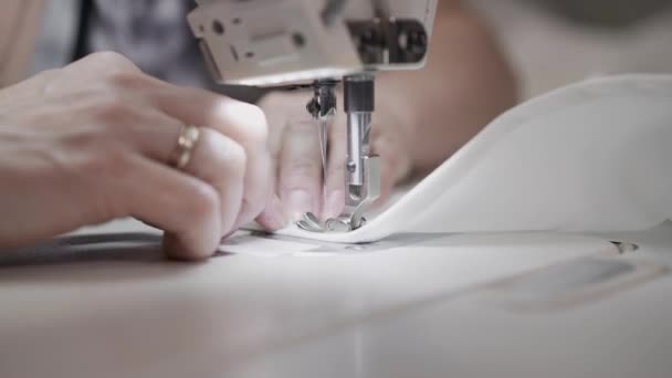 Gimbal shot close up of adult female hands sewing sides of t-shirt — Stock Video