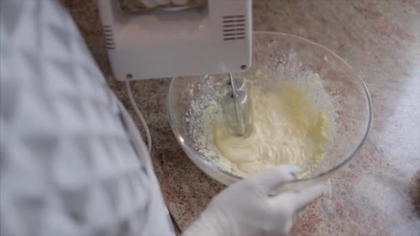 Закройте руки повара смешивая тесто торта в стеклянную миску — стоковое видео