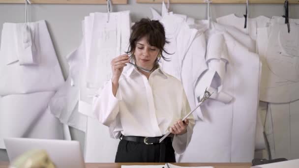 Tiro médio de designer de moda feminina colocando óculos e fazer notas — Vídeo de Stock