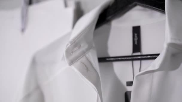 Λευκό πουκάμισο με μαύρη ετικέτα σε μαύρη κρεμάστρα στο στούντιο μόδας — Αρχείο Βίντεο