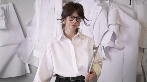 Diseñadora femenina con una carpeta de portapapeles mirando a la cámara — Vídeo de stock