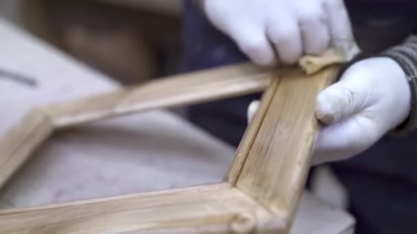 Мужские руки полируют деревянную раму в мастерской по деревообработке — стоковое видео