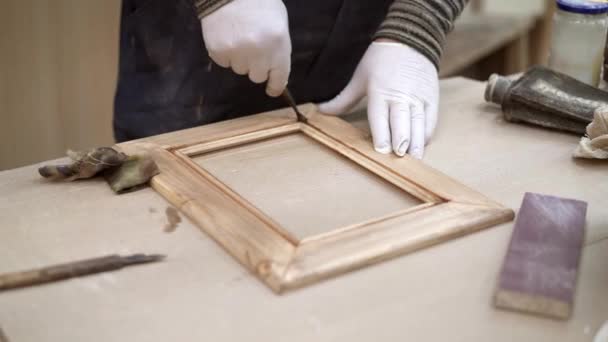 Mãos masculinas com uma pequena escova de pintura óleo moldura de madeira deitada na mesa — Vídeo de Stock