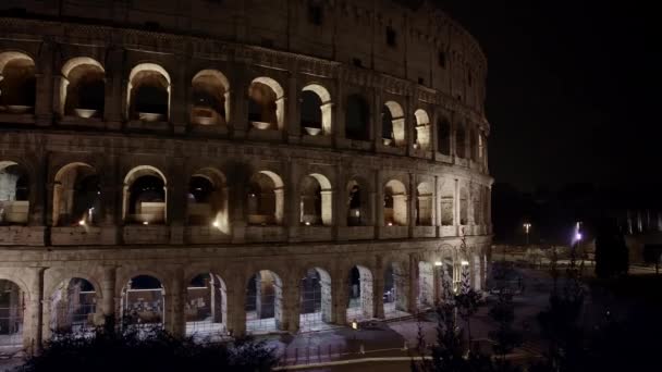 ローマのコロッセオ近くの夜のトラフィックの左から右のリアルタイムパンショット。また、フラビアン円形劇場として知られているコロッセオ、ローマ、イタリアの都市の中心部に楕円形の円形劇場 — ストック動画