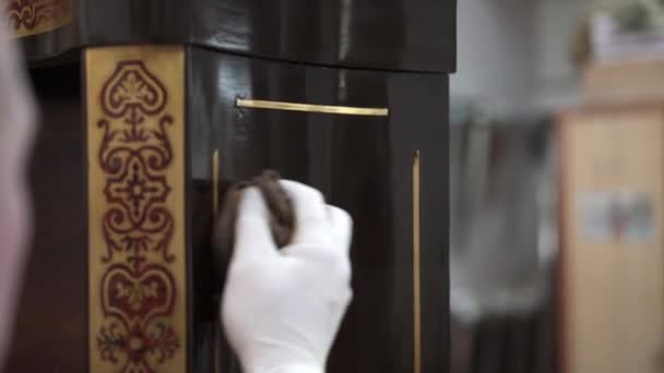 Tilt down close up of male hand polishing a side of brown cupboard with a rag — Stock Video
