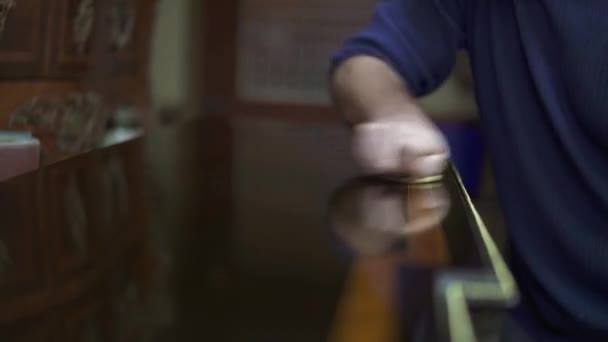 Κοντινό-up του αρσενικού στίλβωσης χέρι ένα καφέ ξύλινο τραπέζι με ένα πανί — Αρχείο Βίντεο