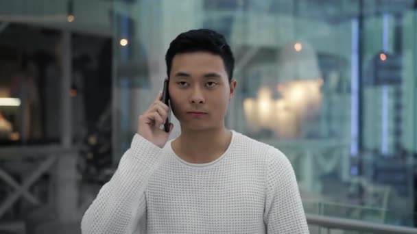Μεσαίο σφηνάκι από ασιατικό αρσενικό μιλάει στο τηλέφωνο, ενώ περπατάει — Αρχείο Βίντεο