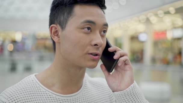 Gros plan de asiatique mâle parler sur le téléphone dans le centre commercial — Video