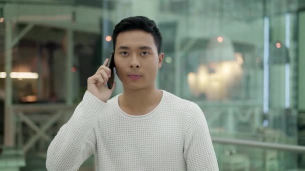 Cámara lenta en el medio disparo de asiático macho hablando por teléfono mientras camina — Vídeos de Stock