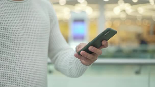 Pan de tiro de mano masculina desplazando un teléfono sobre fondo amarillo borroso — Vídeo de stock