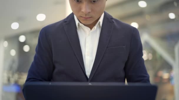 Inclinado hasta tiro de asiático hombre de negocios en traje de trabajo con el ordenador portátil en sus rodillas — Vídeo de stock