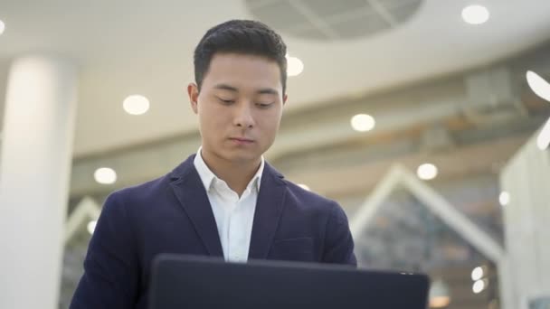 Primer plano de asiático hombre de negocios en traje de trabajo con el ordenador portátil en sus rodillas — Vídeo de stock