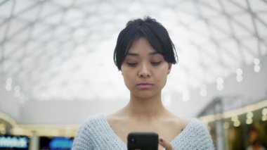 Tavan arka planda Asya kadın kaydırma telefon yavaş hareket portre çekimi