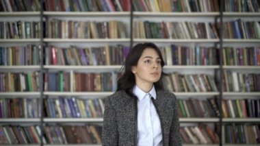 Young asian woman black hair woman pointing at a book on a bookshelf