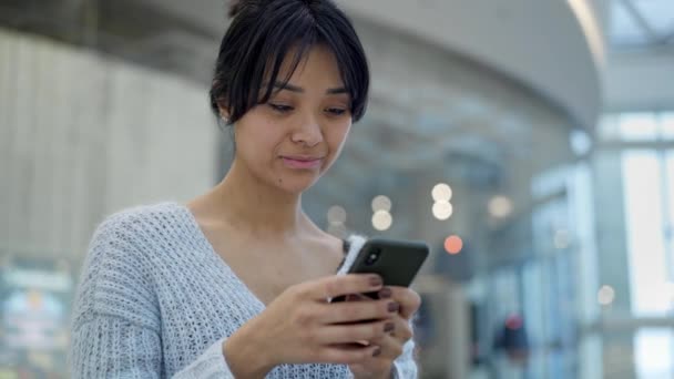 Médio tiro de triste ásia feminino de pé mensagens de texto no telefone — Vídeo de Stock