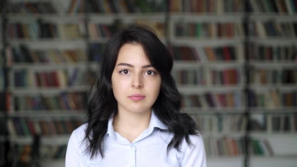 Close-up portret van Aziatische jonge vrouw op achtergrond van bibliotheek planken — Stockvideo