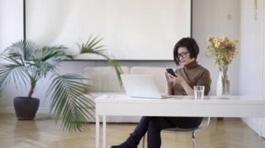 Asyalı kadın beyaz ev ofis oturan telefon kaydırma