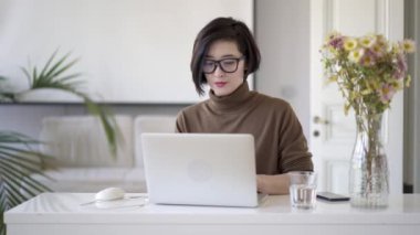 Beyaz ev ofis dizüstü bilgisayar da yazma gözlük Asyalı kadın
