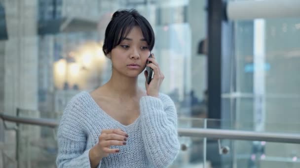 Middle shot of sad asian female standing talking on phone — Stock Video