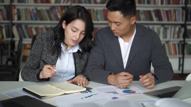 Asiatique jeune couple homme et femme discuter projet dans bibliothèque — Video