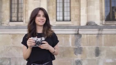 Siyah tişörtlü koyu saçlı neşeli genç kadın fotoğraf çekiyor. Yavaş çekim portre çekimi.