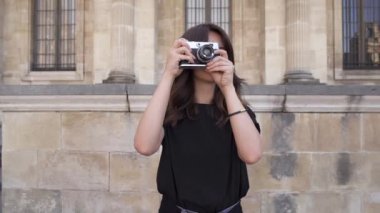 Siyah tişörtlü koyu saçlı neşeli genç kadın fotoğraf çekiyor. Yavaş çekim portre çekimi.