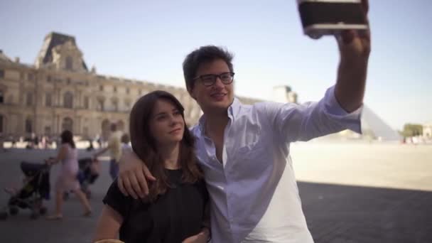 Une belle jeune femme aux cheveux foncés dans un t-shirt noir et jeune homme joyeux dans une chemise prendre un selfie. Prise de vue portrait au ralenti . — Video