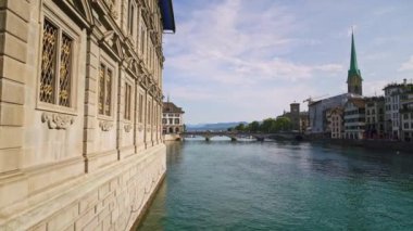 Zürih, İsviçre - Nisan 2019: Zürih'te ilkbahar da pan çekimi, yoldan geçen araba köprüsü ve gün ışığında Limmat